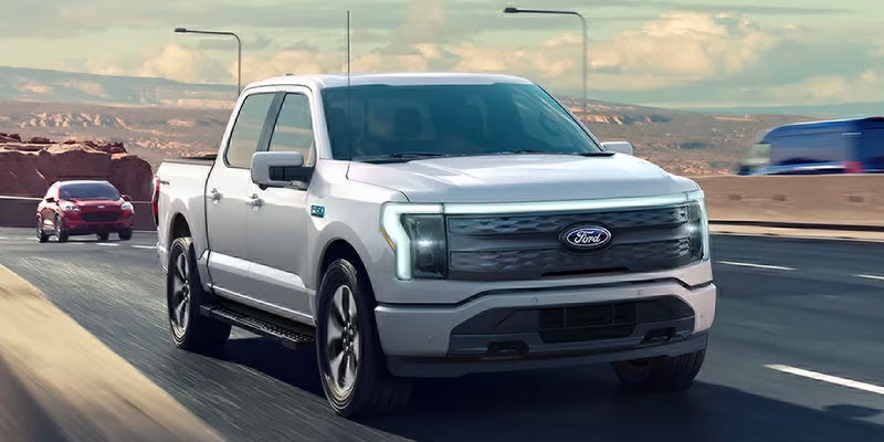 White Ford F-150 Lightning electric pickup truck driving on a highway